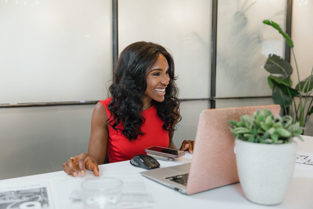 A woman in a red dress sitting in front of a laptop: outsourcing functions