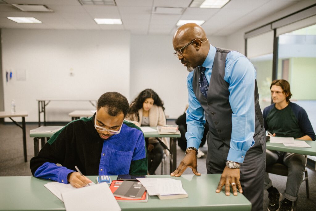 A professor standing by a student's desk