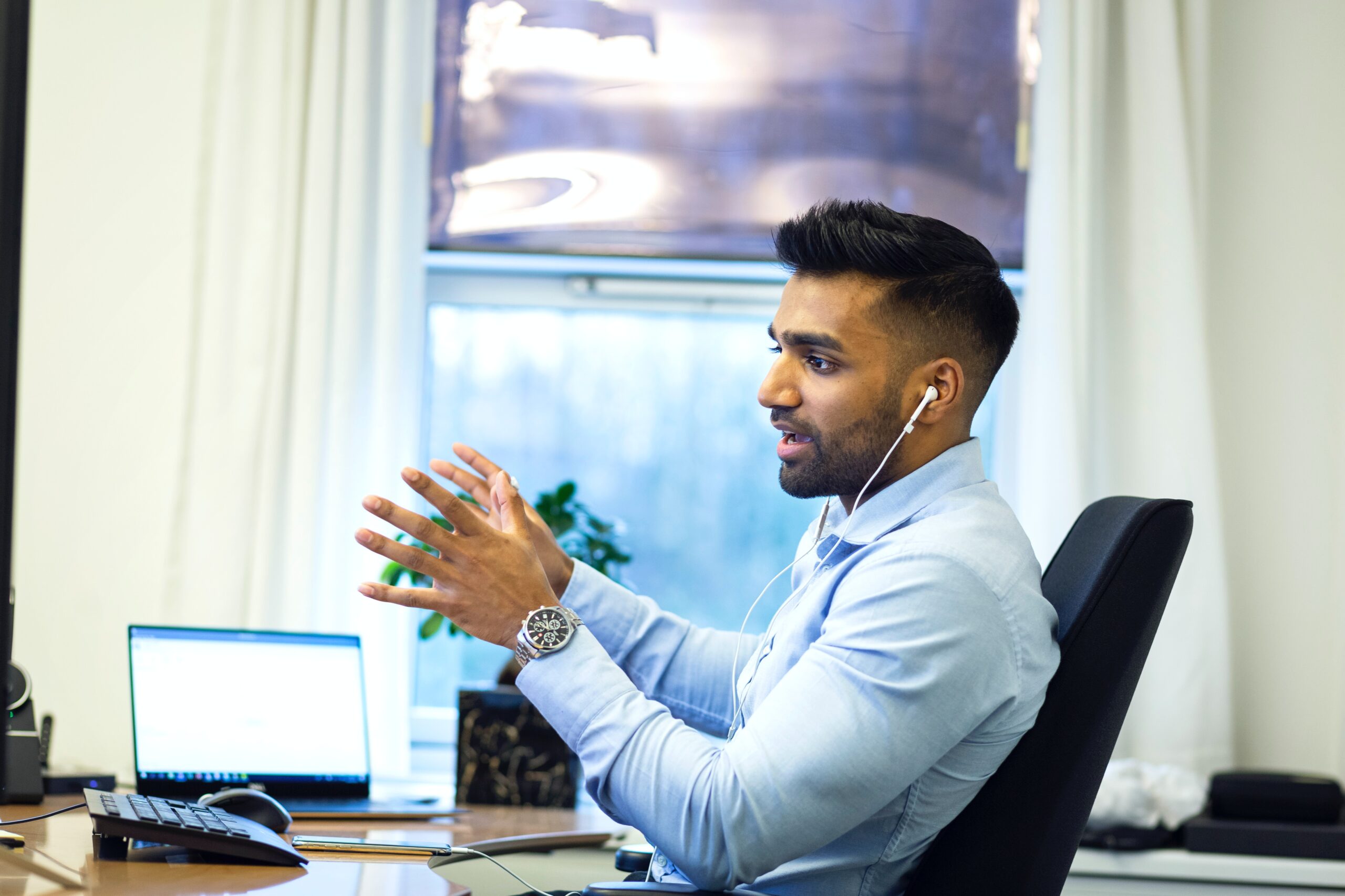 A man in a blue shirt sitting at a desk having a meeting: outsourced finance services