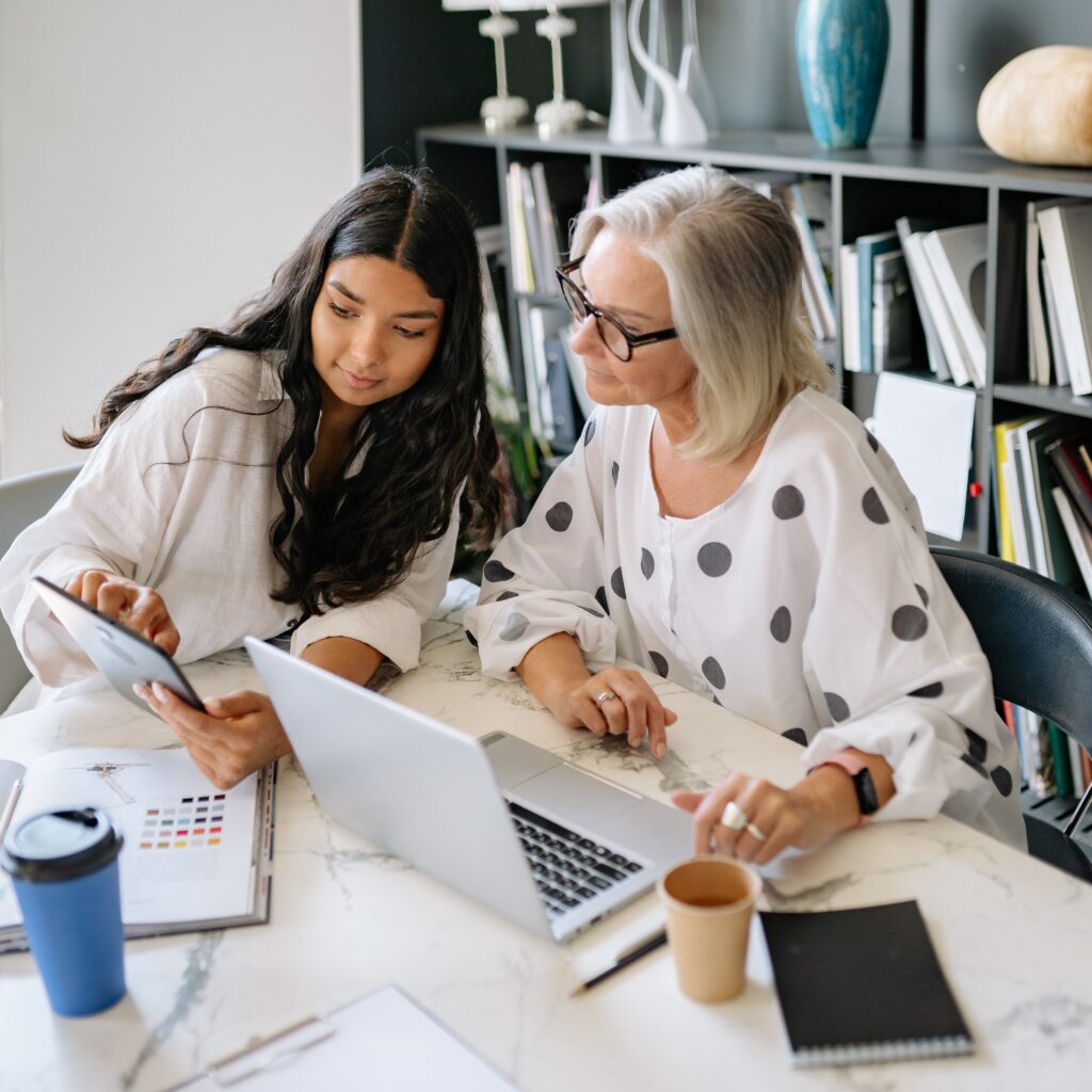 Two women sitting in front of a laptop having a discussion: outsourced marketing