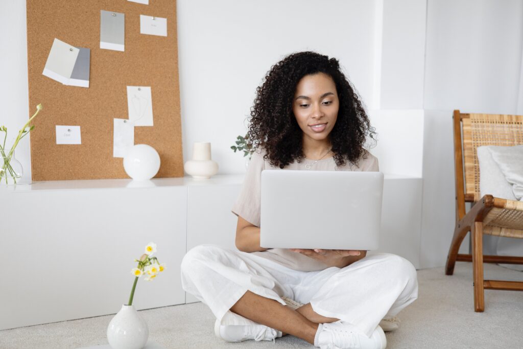 A woman sitting on the floor using a laptop: outsourced communications