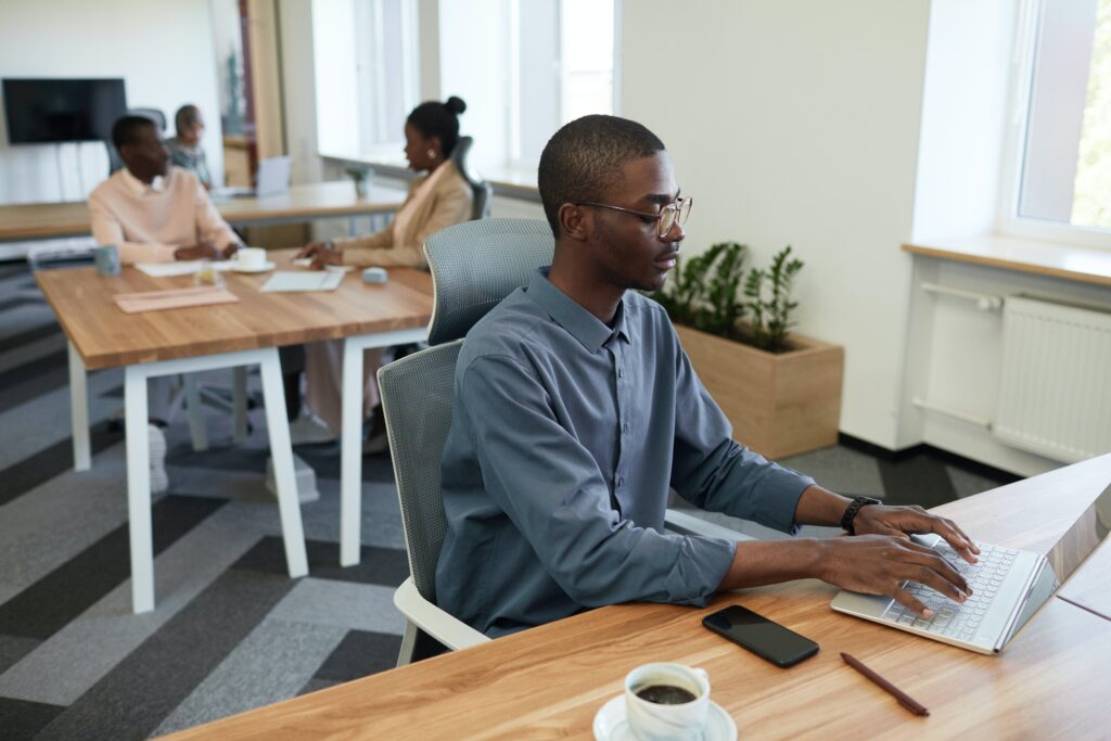 A man in a grey long-sleeve shirt working on his laptop: outsourced communications
