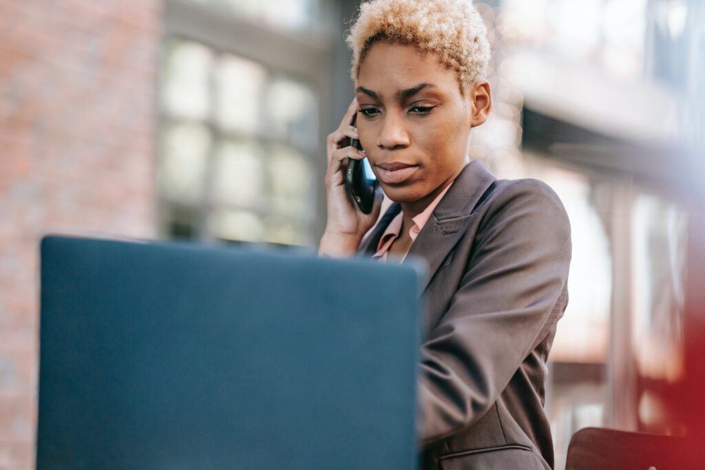Woman calling on phone while working on a laptop: outsourced social media