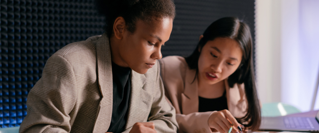 Two women at a desk working on a plan together: remote team