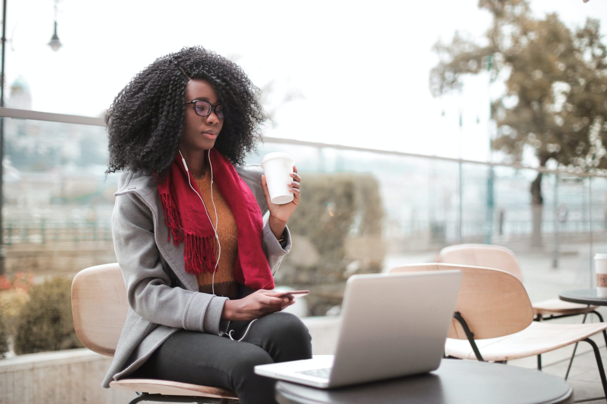 A woman having coffee and working from outside: outsourced virtual assistant
