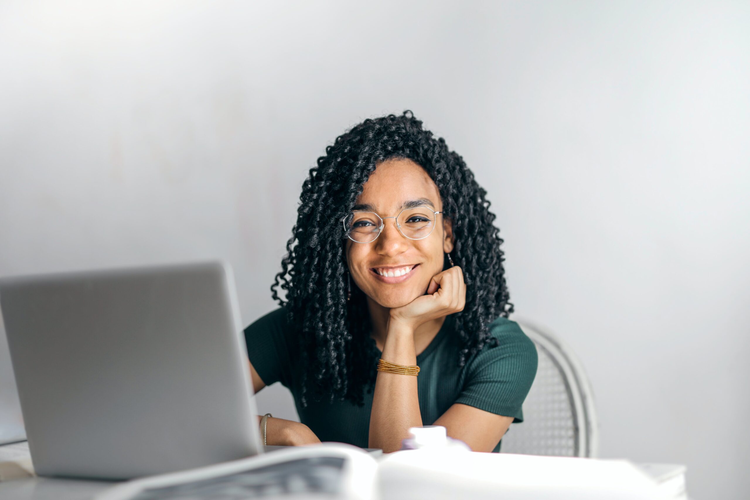 A happy woman sitting at a table with a laptop: outsourced receptionist