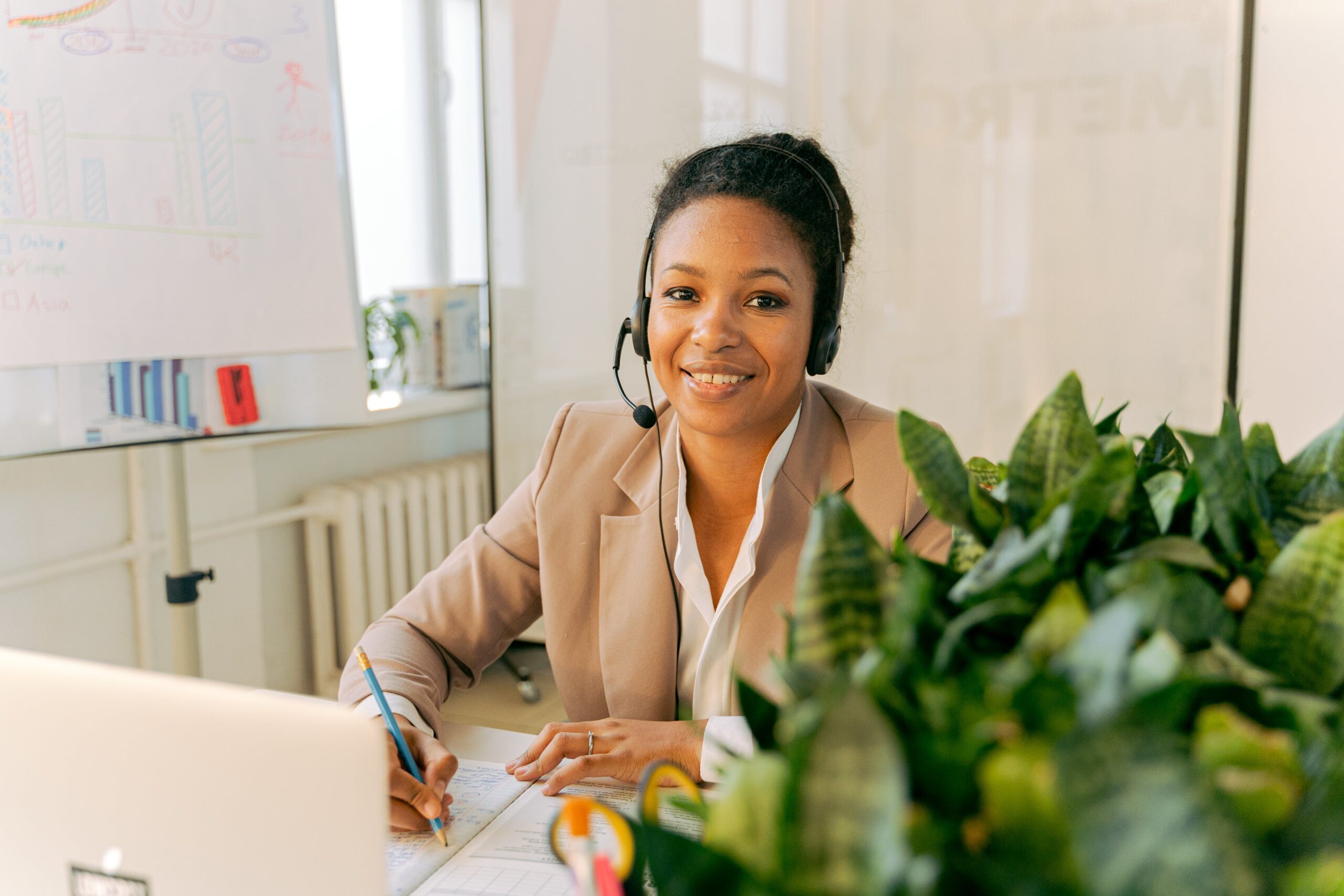 A woman sitting at a table wearing black headphones: outsourced call centre