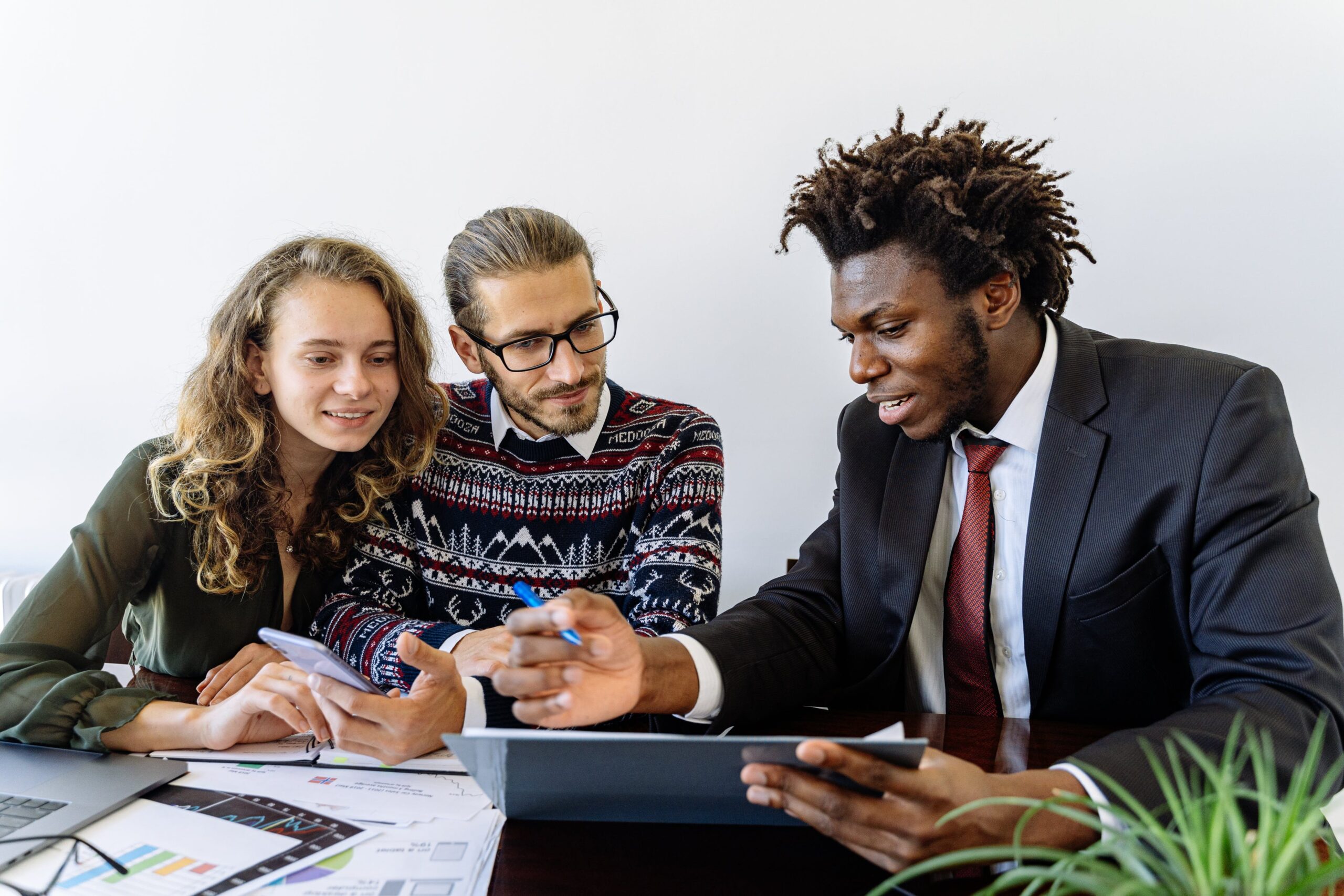 A man in a black suit showing something to a couple at a table: outsourced sales representative