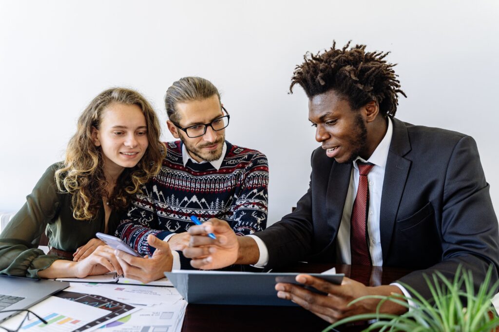 A man in a black suit showing something to a couple at a table: outsourced data entry