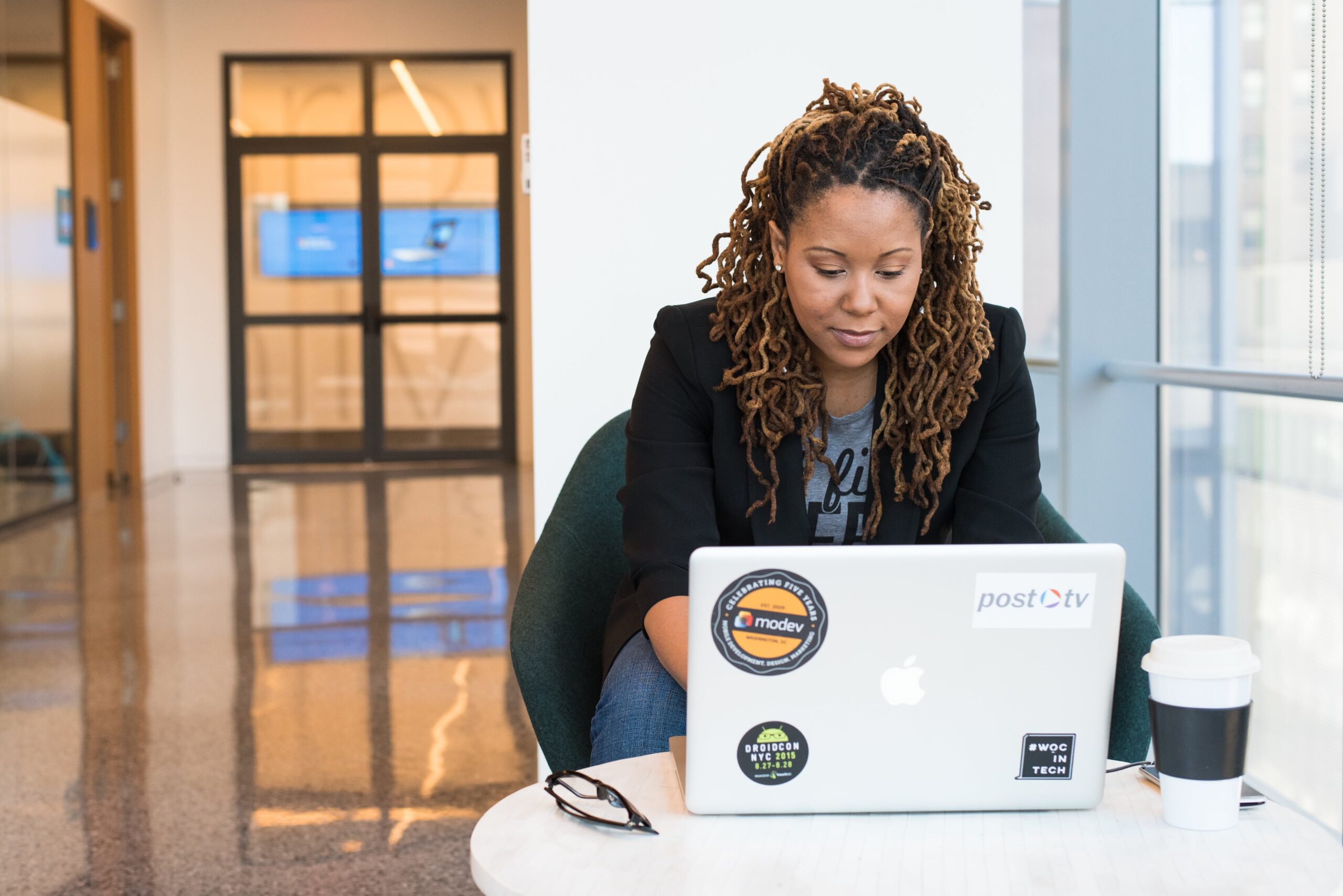 Woman in black blazer sitting on chair using laptop: outsourced live chat