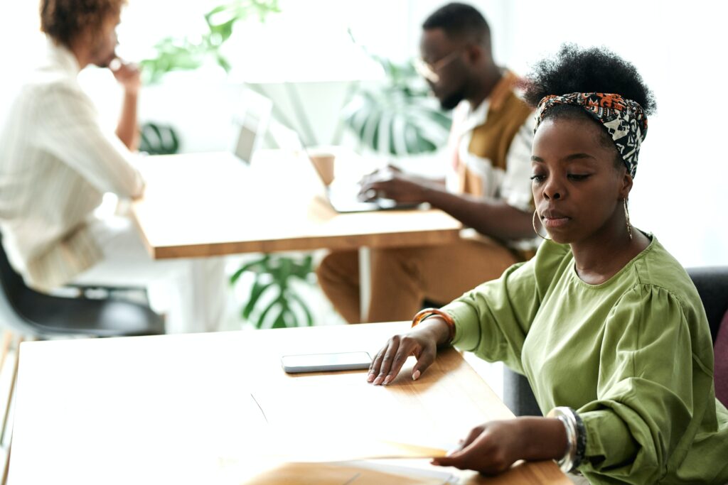 A woman seated at a wooden table looking at documents: outsourcing risk management