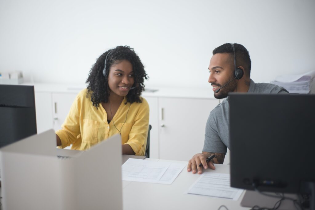 Woman and man seated at a desk consulting: outsourced live chat