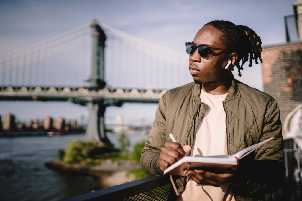 Contemplative man in wireless headphones writing in notebook: outsourced call centre