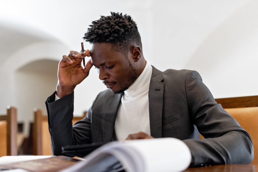 A man in a grey suit sitting at a table thinking: outsourced data entry
