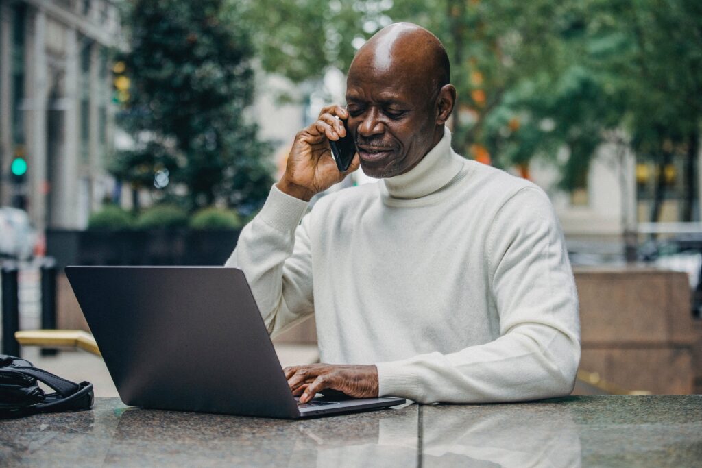 A man talking on the phone while using a laptop: outsourced call centre