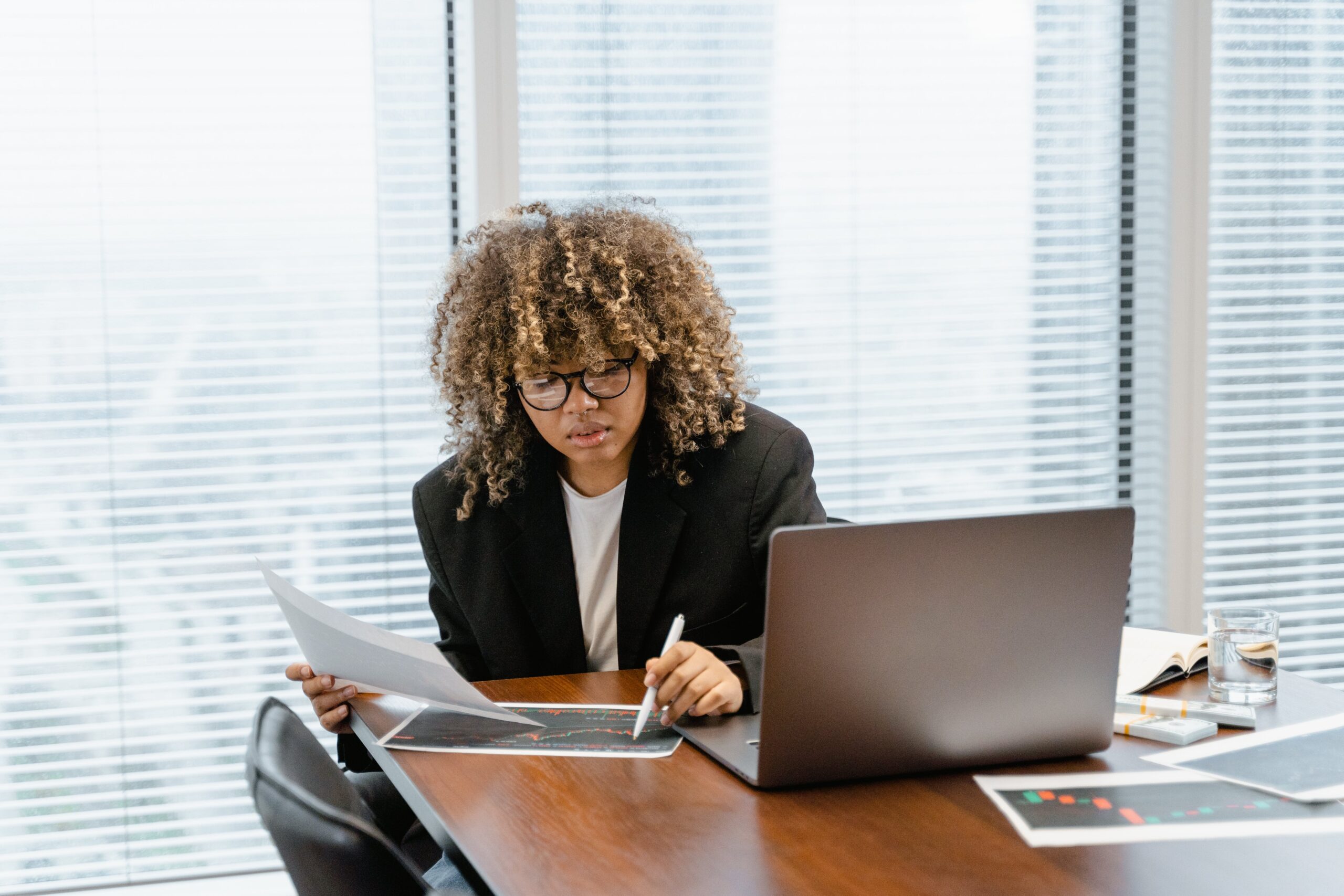 A woman seated at a desk with her laptop open working on some documents: outsourcing risk management