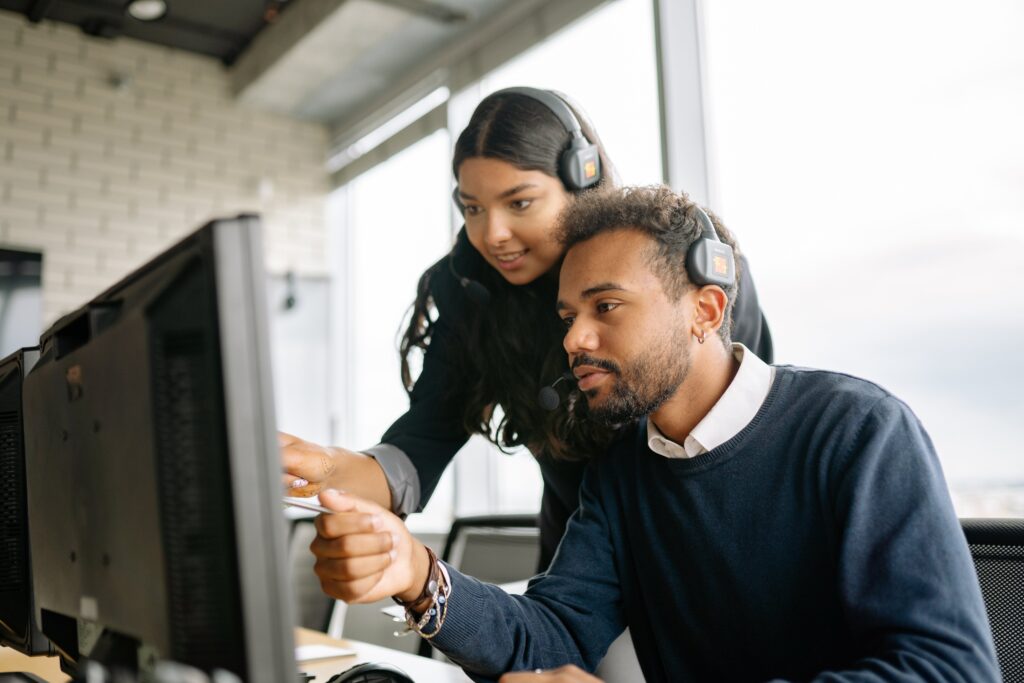 A man and a woman working on something on a computer: outsourced call centre